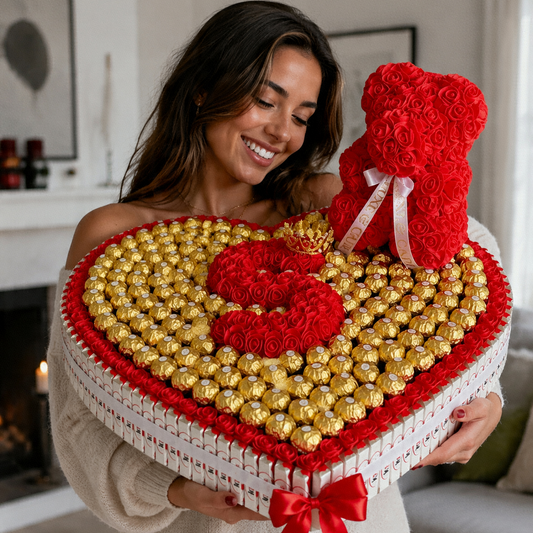 
Femme souriante tenant un grand plateau en cœur rempli de Ferrero Rocher avec un ourson en roses rouges et une initiale personnalisée au centre.